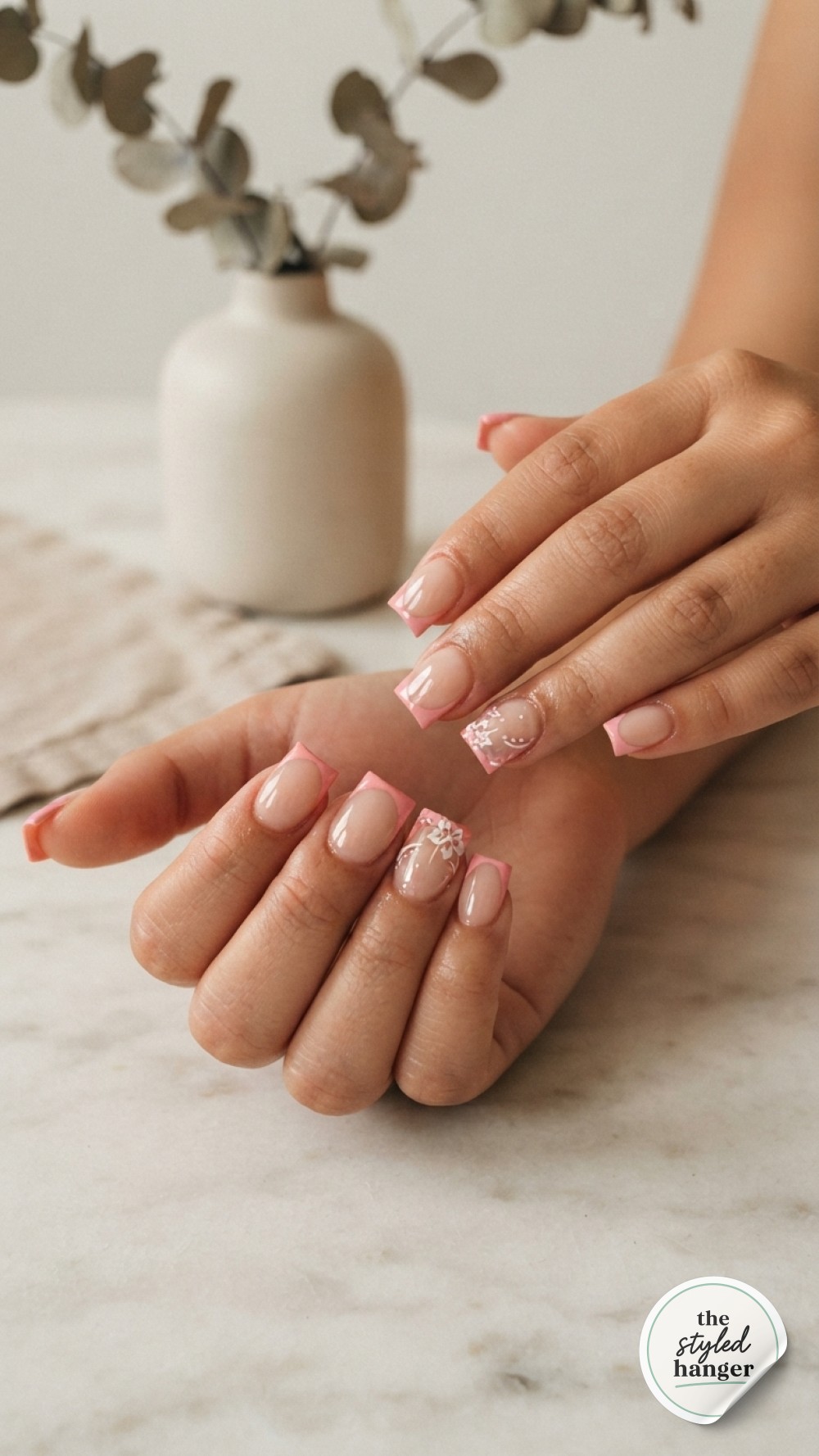 Soft coral-pink short oval nails wrap around a delicate teacup in warm golden café light.